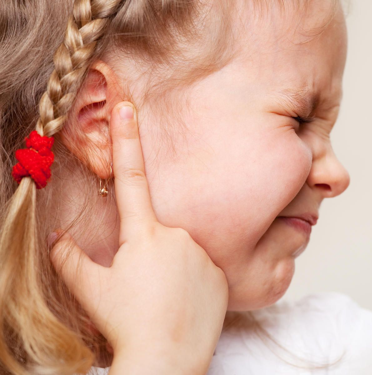 Girl suffering from ear infection and experiencing pain