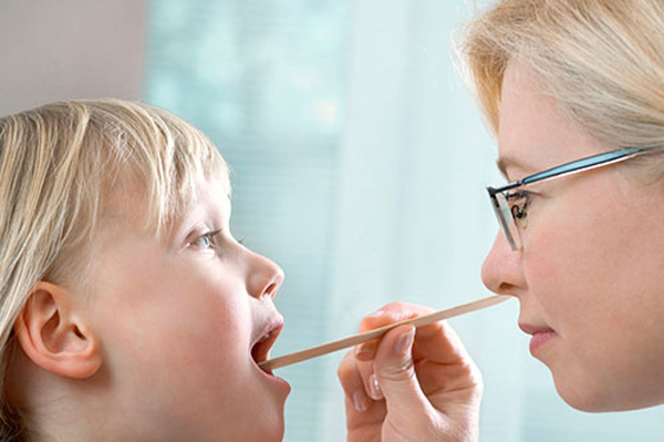 Pediatrician examining child's throat